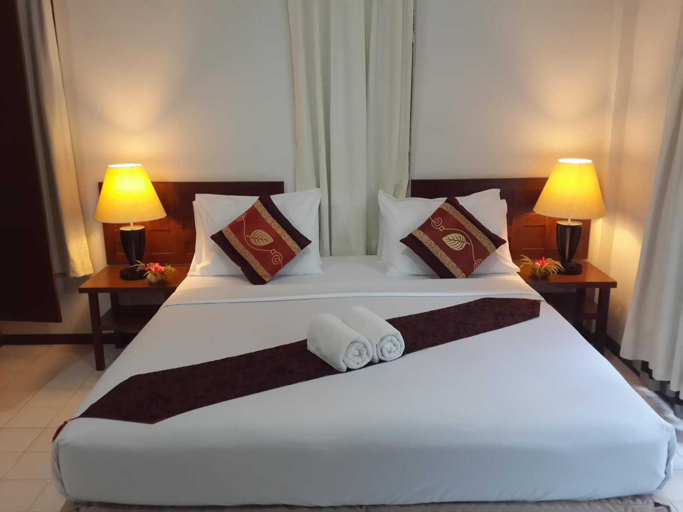 Double bed with matching cushions and bedside lamps at Baan Chaba Bungalow