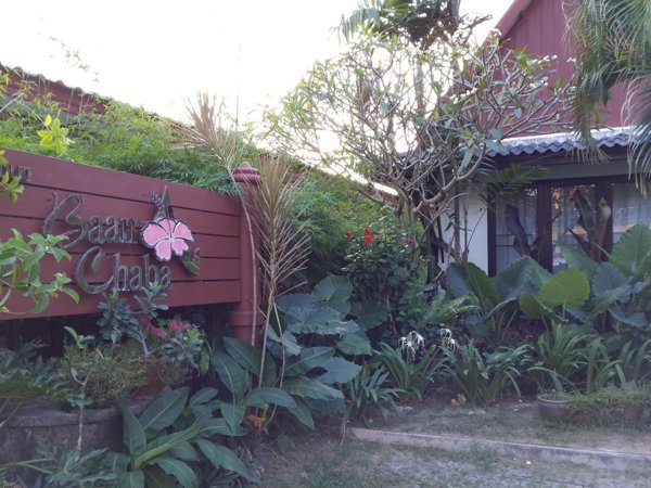 Baan Chaba sign and bungalow entrance among garden plants
