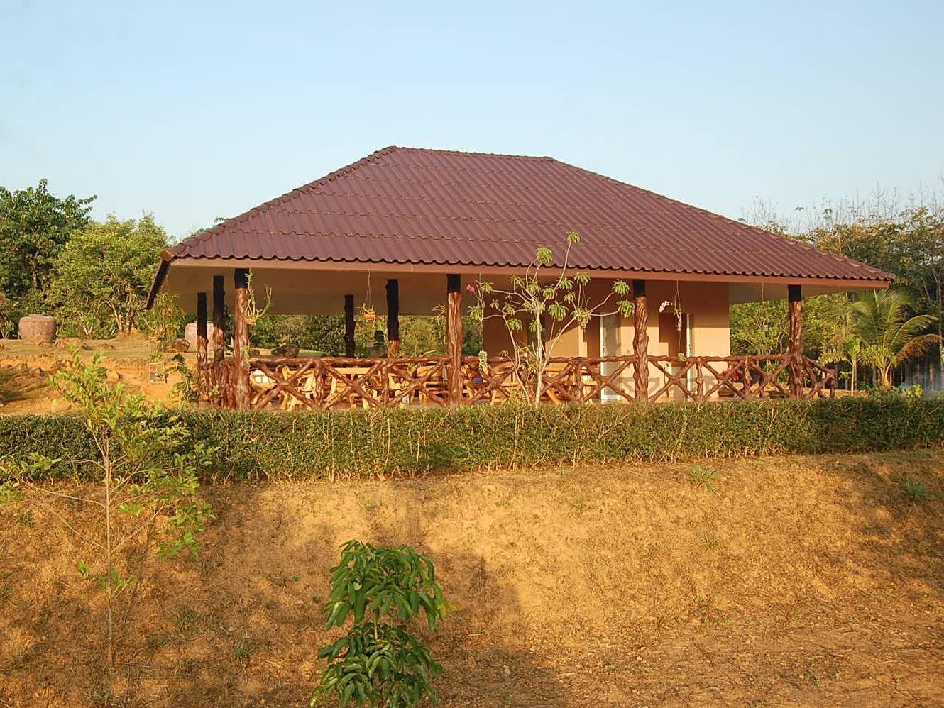 Red-roofed bungalow with a covered veranda on a grassy slope
