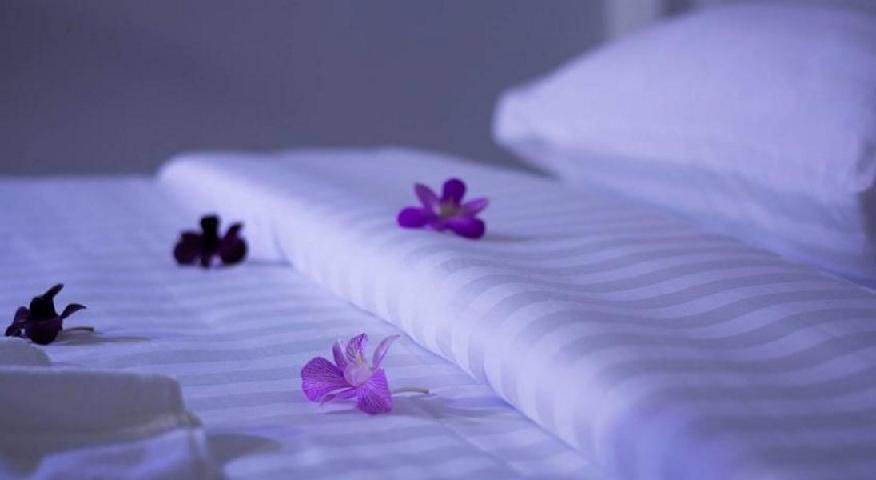 Folded white towels decorated with purple flowers at Muen Chang Nan Boutique Hotel