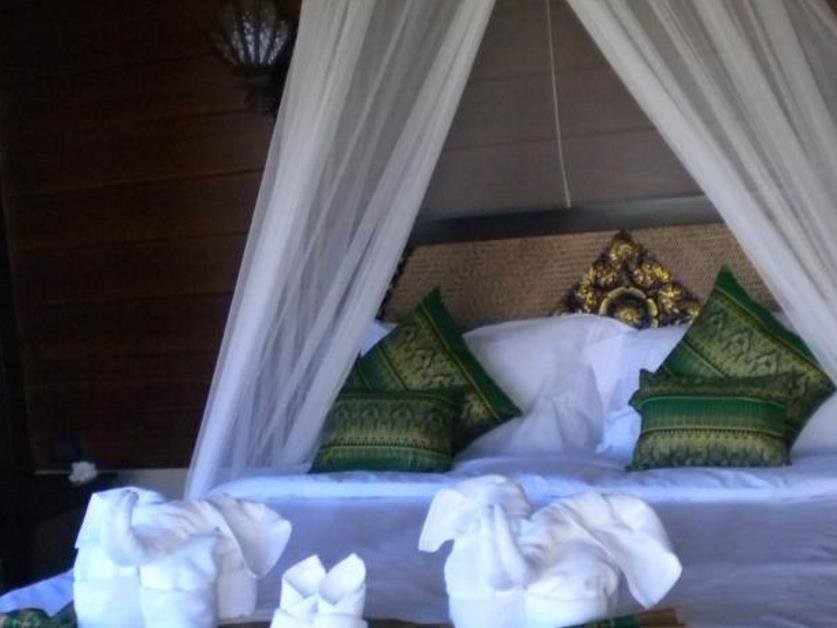 Canopied double bed with cushions and towel decorations at Shambave Pai Resort