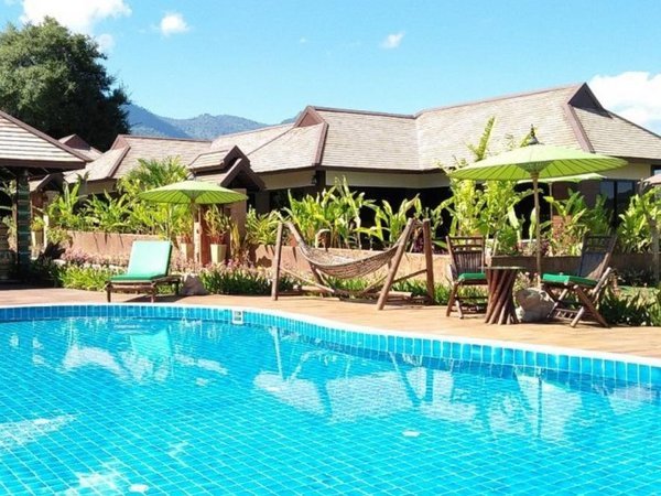 Swimming pool with loungers and bungalow buildings at Shambave Pai Resort