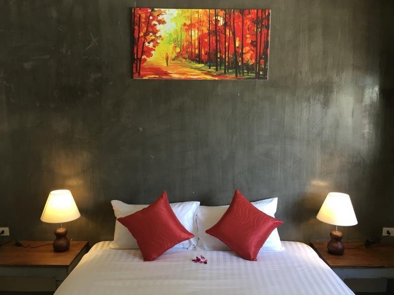 Double bed with red cushions beneath a forest picture at The Morning Minihouse Aonang